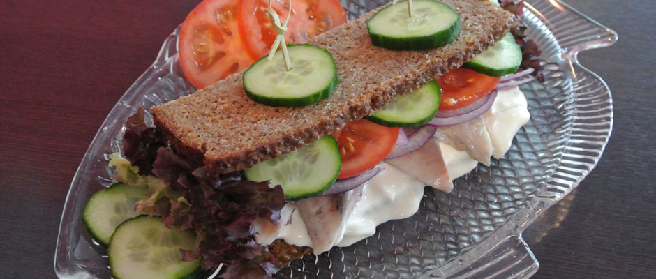 Matjes-Sandwich mit frischem Gemüse auf einem Fischteller