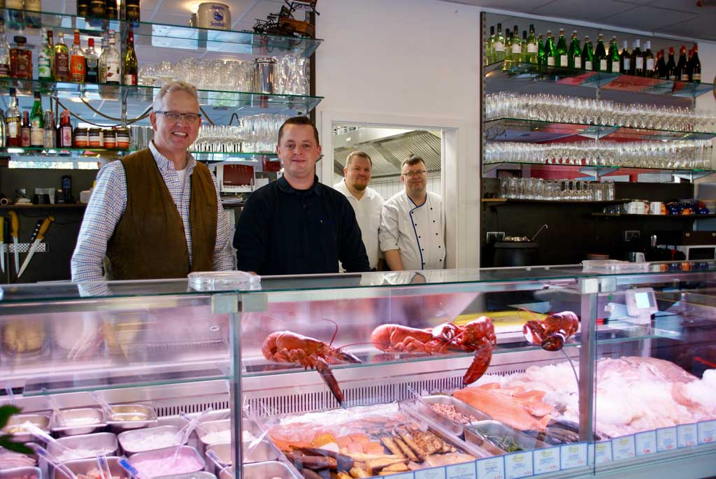 Inhaber und Team hinter der Theke mit frischem Hummer